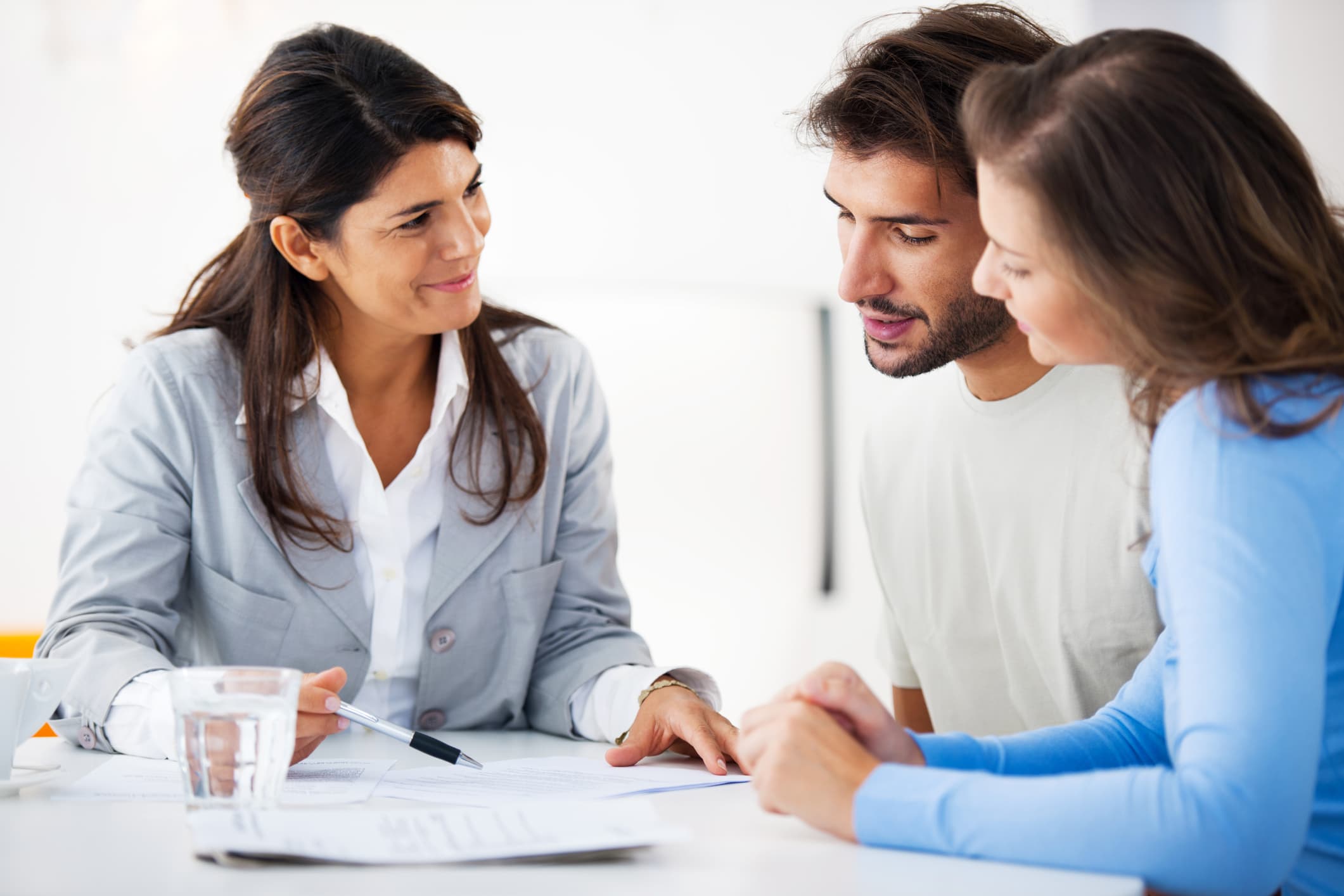 a woman helping a couple with financial paperwork